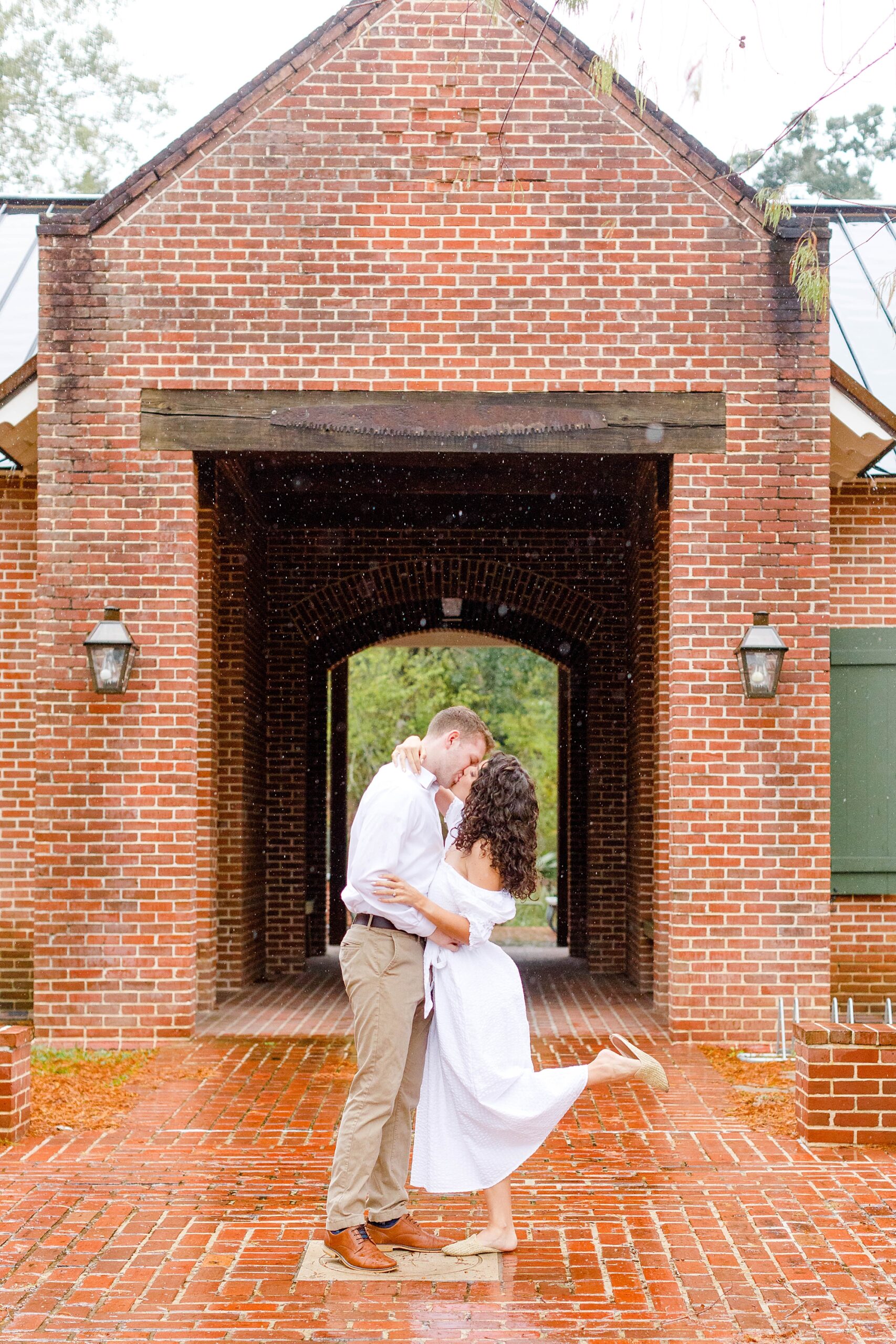 engaged couple kiss near brick building