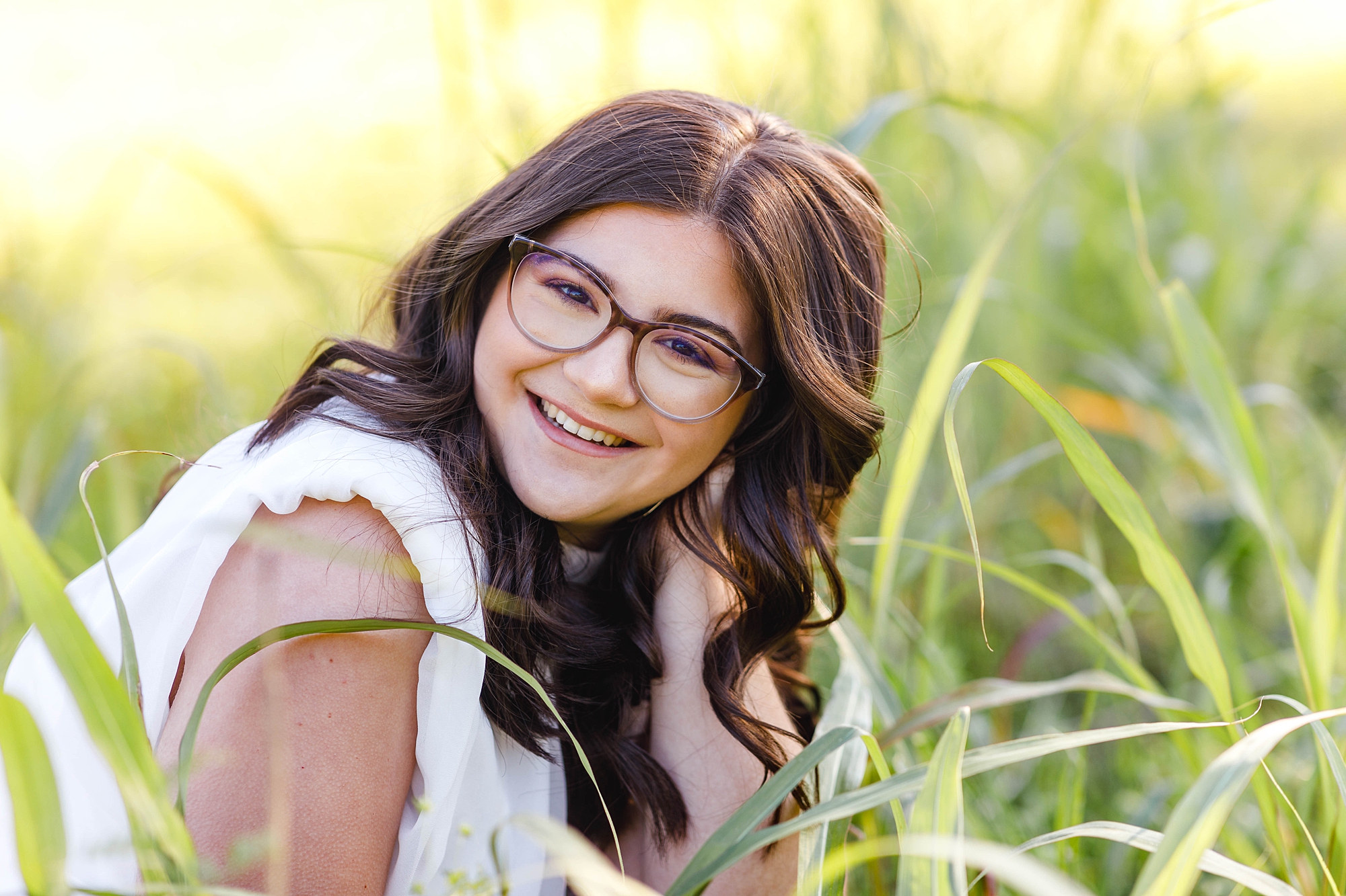 senior sits in tall grass from 2023 Senior Sessions 