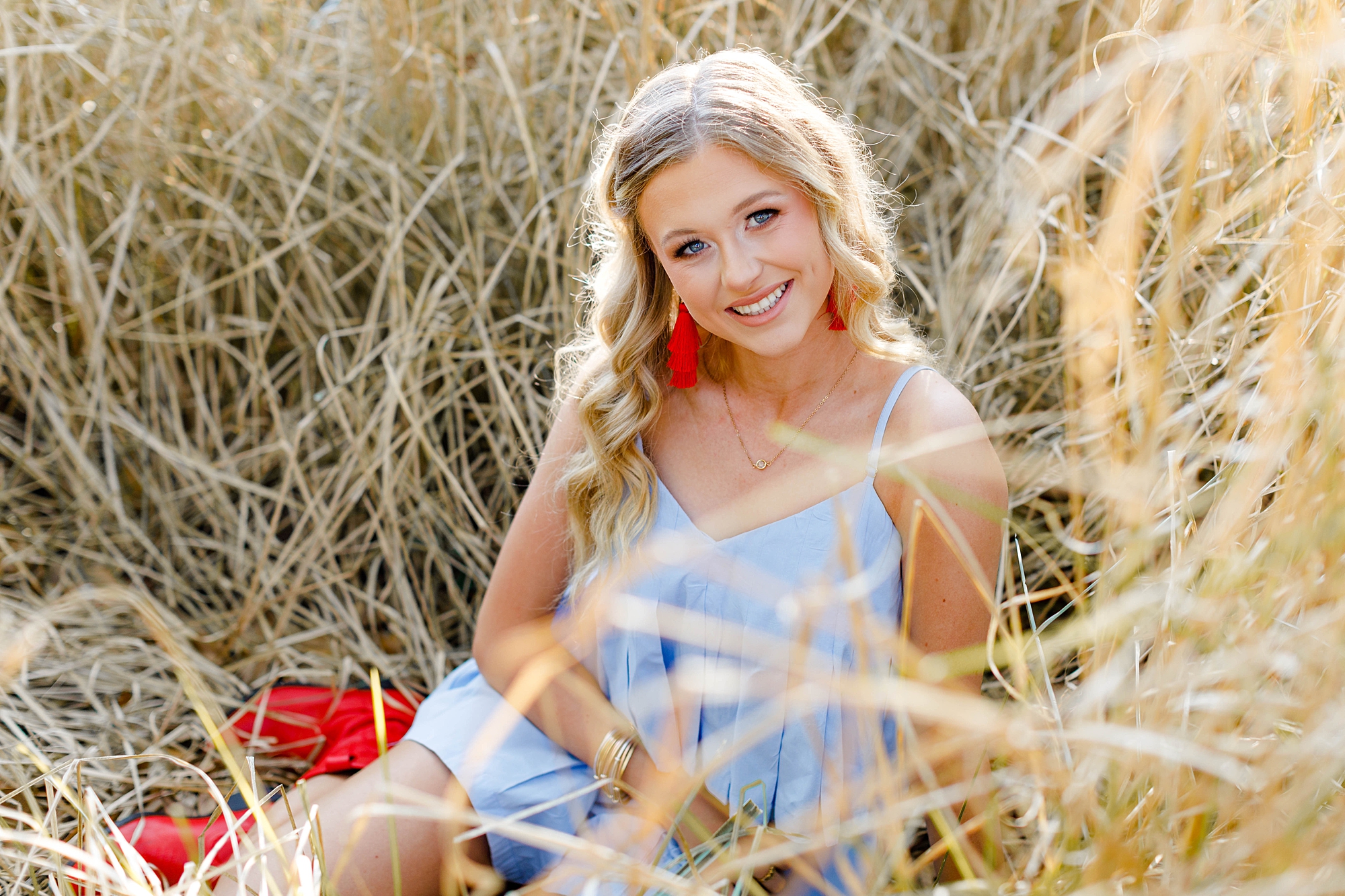 2023 Senior Sessions of girl sitting in tall grass 